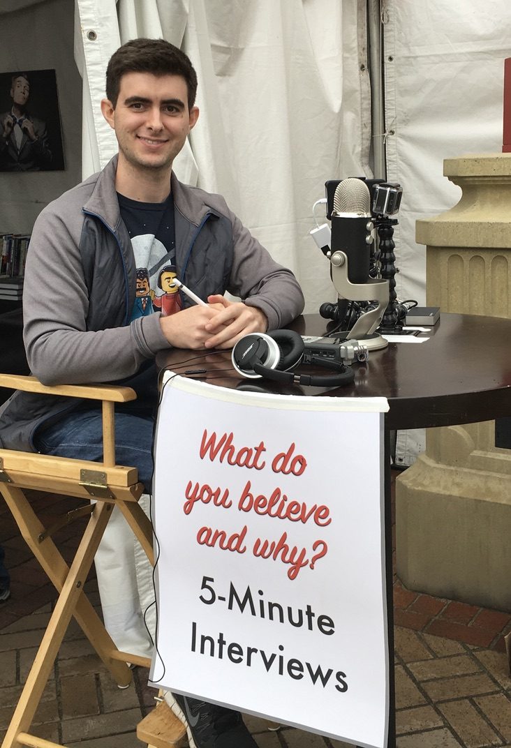 Reid sitting at a small table with a 5-Minute Interviews sign at the LA Festival of Books